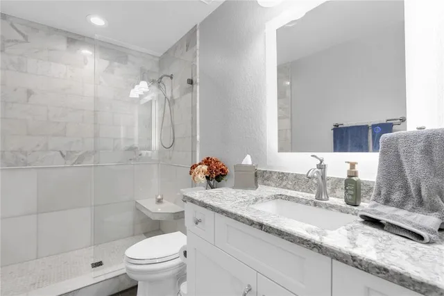 a bathroom with a granite countertop double vanity sink toilet and shower