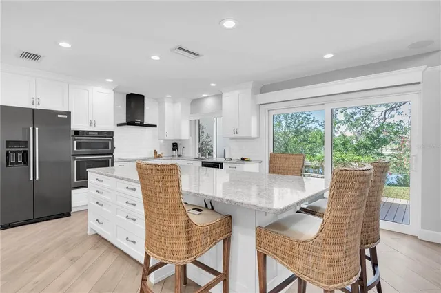 a kitchen with stainless steel appliances granite countertop a stove a refrigerator a kitchen island and chairs