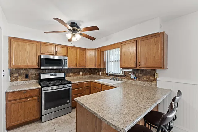 a kitchen with kitchen island granite countertop a stove top oven a sink a counter space and cabinets