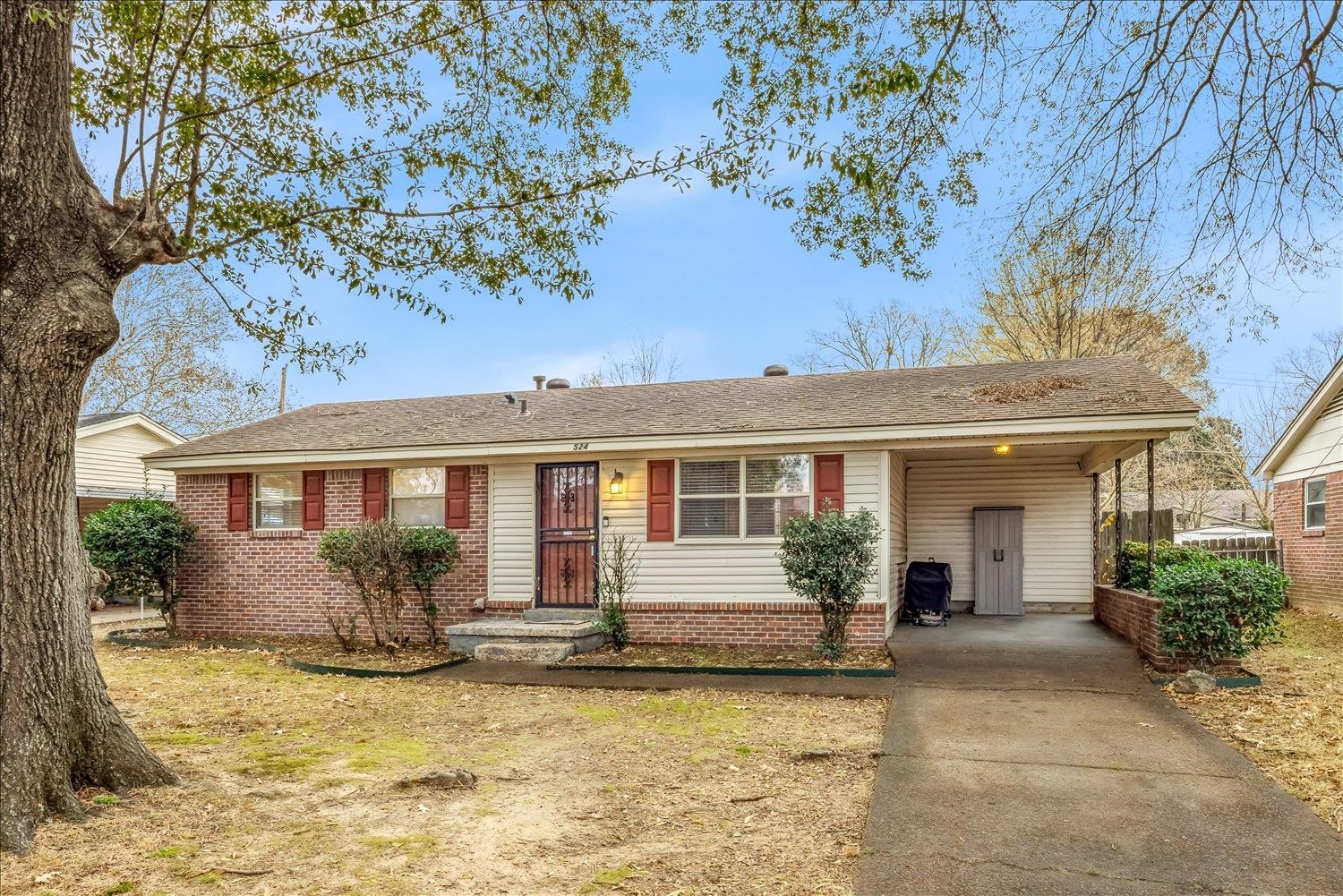 front view of a house with potted plants and a large tree