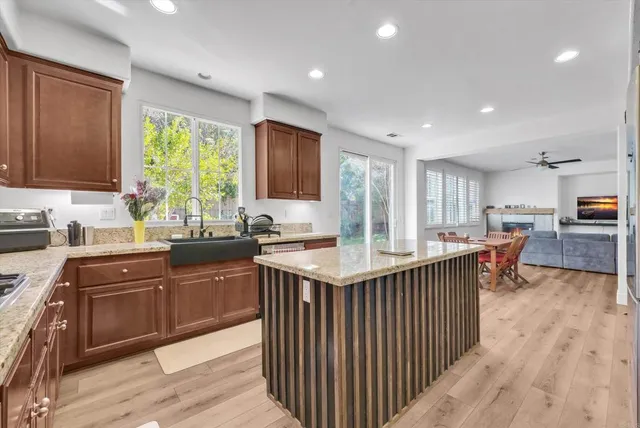 a kitchen with stainless steel appliances granite countertop a table chairs sink and cabinets