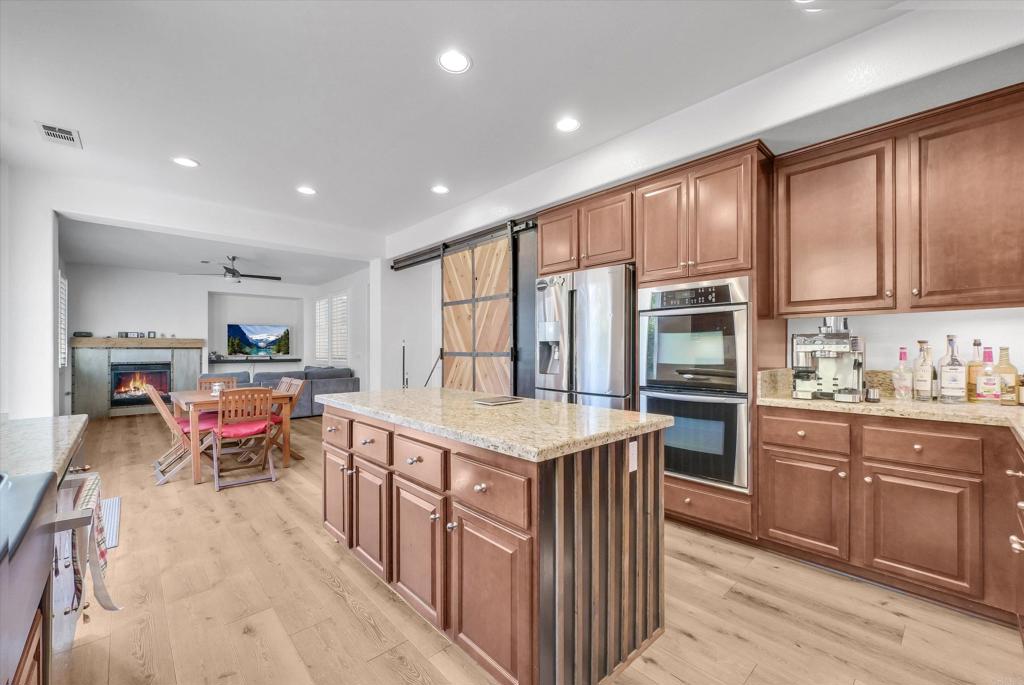45418 Seagull Way Temecula, CA 92592 - Photo 12 of 31 a kitchen with stainless steel appliances granite countertop a stove top oven a sink dishwasher and a refrigerator with wooden cabinets