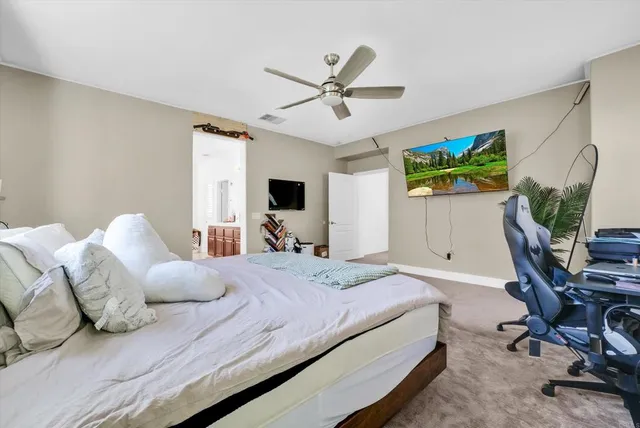 a bedroom with a bed a computer on the desk and a book shelf