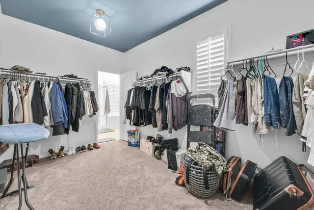 a walk in closet with clothes and shoes