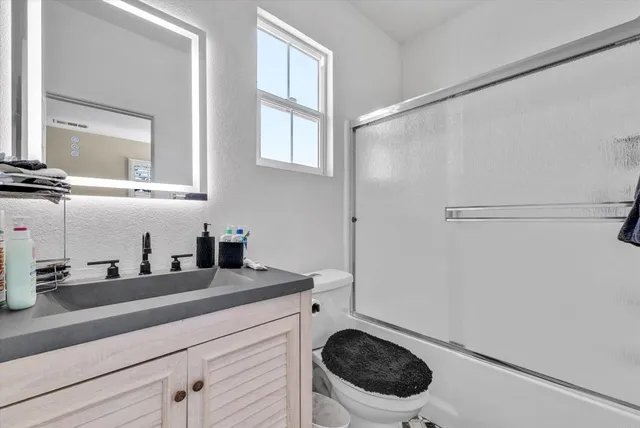 a bathroom with a granite countertop sink a toilet and a mirror