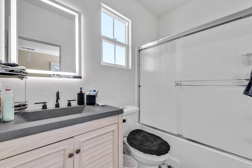 45418 Seagull Way Temecula, CA 92592 - Photo 25 of 31 a bathroom with a granite countertop sink a toilet and a mirror
