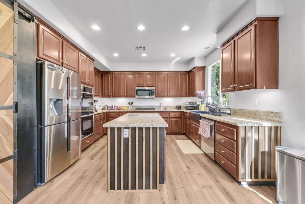 45418 Seagull Way Temecula, CA 92592 - Photo 10 of 31 a kitchen with stainless steel appliances granite countertop a refrigerator a stove a sink and a microwave oven with wooden floor