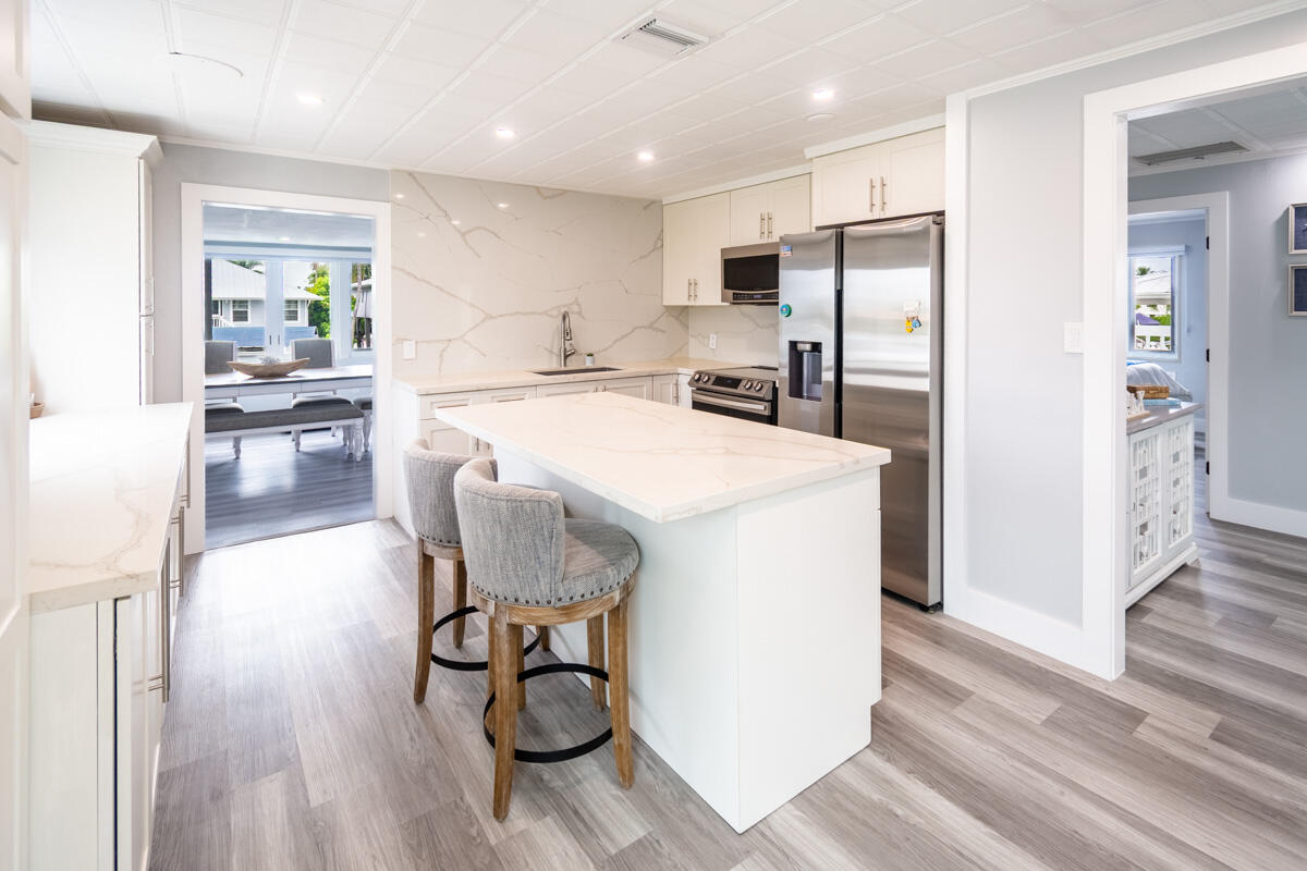 576 Coconut Avenue Goodland, FL 34140 - Photo 6 of 38 a kitchen with stainless steel appliances a refrigerator a stove a sink dishwasher and white cabinets with wooden floor