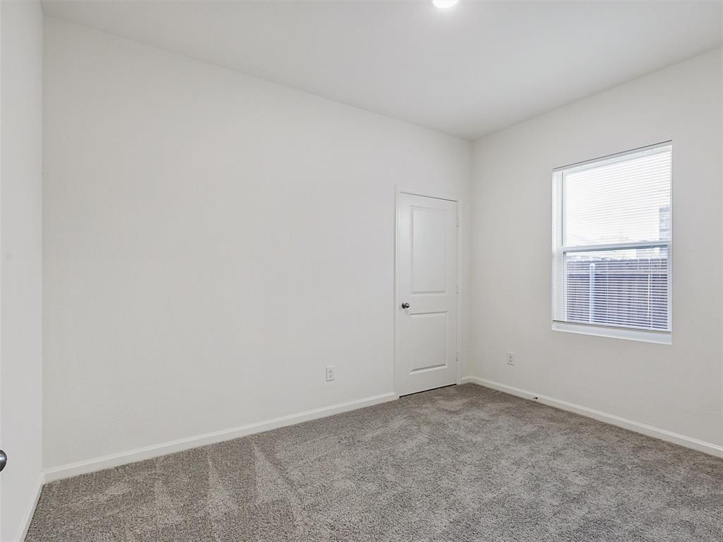 4510 Winecup Road Melissa, TX 75454 - Photo 18 of 22 Bright room featuring a window with blinds, a white paneled door, light-colored walls, and gray textured carpeting