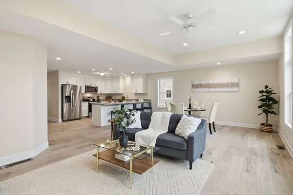 a living room with furniture kitchen view and a potted plant