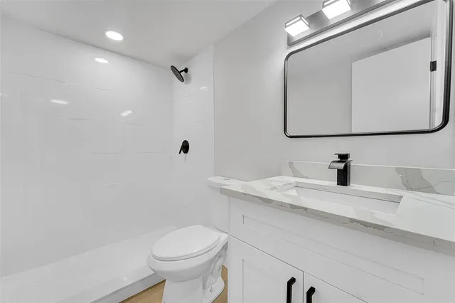 a bathroom with a sink vanity mirror and toilet