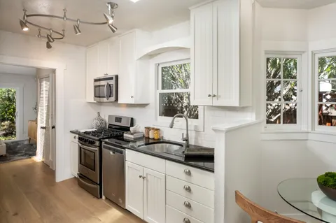 a kitchen with stainless steel appliances a sink a stove a window and cabinets
