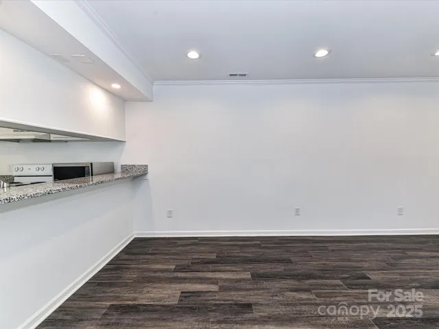 a view of kitchen and empty room with wooden floor