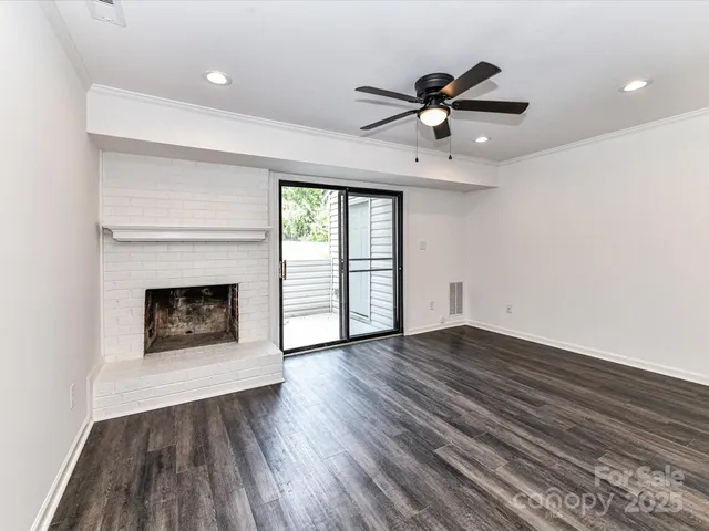 a view of an empty room with wooden floor fireplace and a window