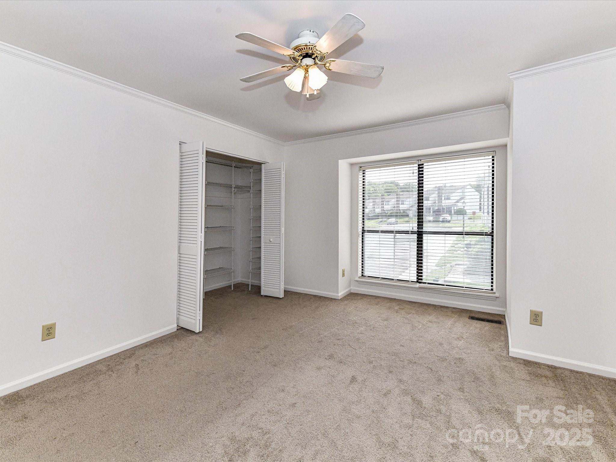 11020 Carmel Crossing Road Charlotte, NC 28226 - Photo 21 of 30 an empty room with chandelier fan and windows