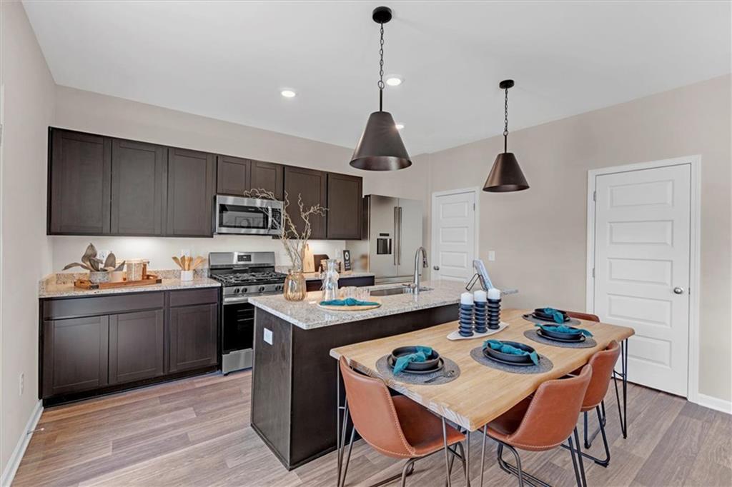 117 Lavender Circle Calhoun, GA 30701 - Photo 10 of 29 a kitchen with a stove a sink a kitchen island with chairs and wooden cabinets