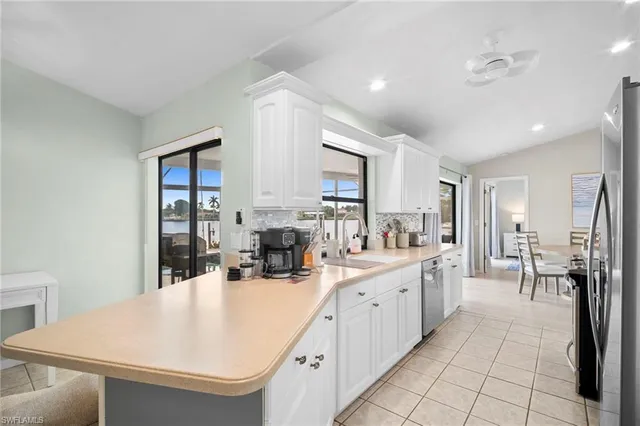 a large white kitchen with a sink and dishwasher a refrigerator with white cabinets
