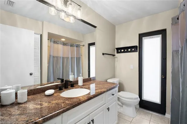 a bathroom with a granite countertop sink a toilet and a mirror