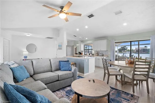 a living room with furniture kitchen view and a large window