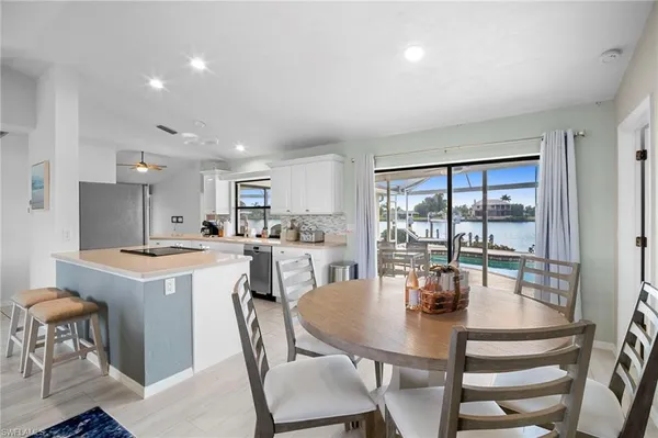 a kitchen with a dining table chairs and white appliances