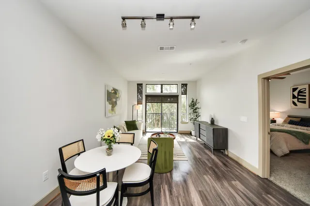 a view of a patio with table and chairs potted plants and floor to ceiling window