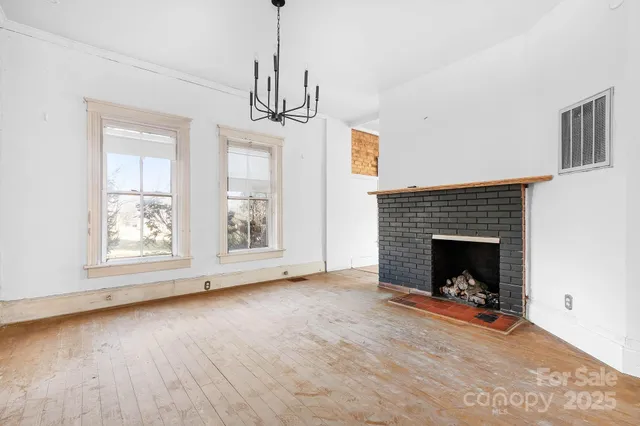 a view of a livingroom with wooden floor a fireplace and window