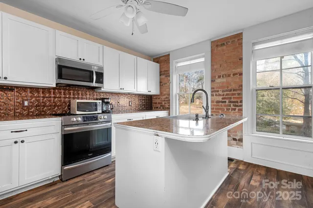 a kitchen with stainless steel appliances granite countertop a sink a stove a refrigerator cabinets and a window