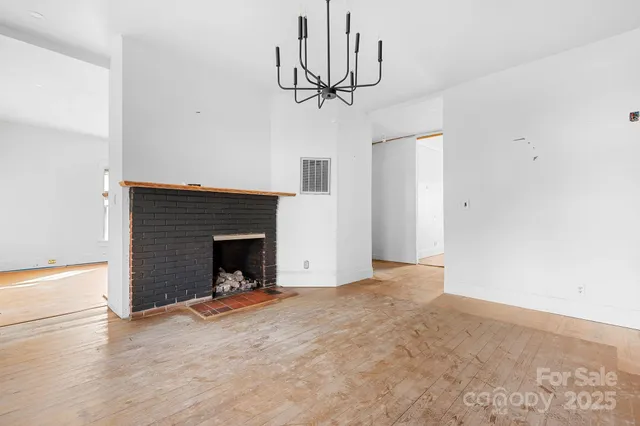 a view of a livingroom with a fireplace a chandelier and stairs
