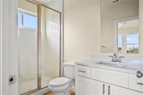 a bathroom with a sink a toilet a mirror and shower