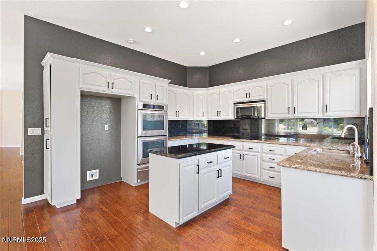 5024 East Albuquerque Road Reno, NV 89511 - Photo 12 of 27 a kitchen with stainless steel appliances granite countertop a refrigerator a sink dishwasher a stove and white countertops with wooden floor