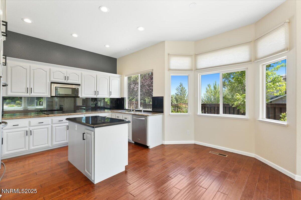 5024 East Albuquerque Road Reno, NV 89511 - Photo 13 of 27 a kitchen with stainless steel appliances granite countertop a stove a sink and white cabinets with wooden floor next to windows