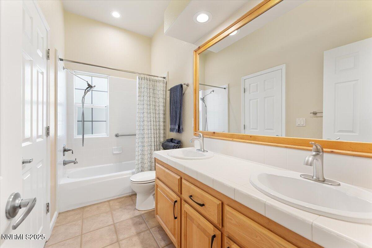 5024 East Albuquerque Road Reno, NV 89511 - Photo 20 of 27 a bathroom with a granite countertop sink a toilet a mirror and bathtub