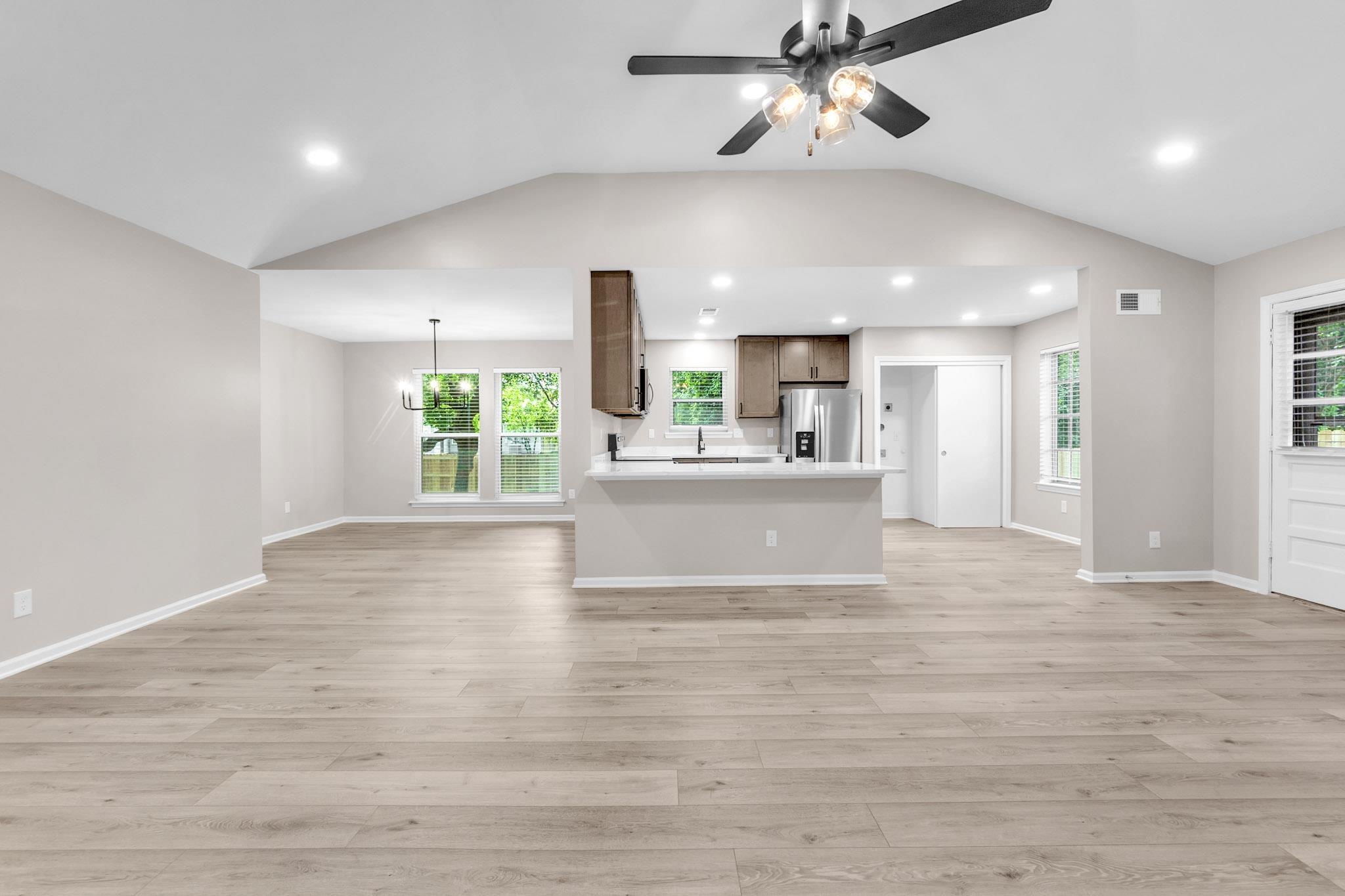 2556 Lynnfield Road Memphis, TN 38119 - Photo 14 of 24 Unfurnished living room with a ceiling fan, light wood finished floors, a chandelier, and vaulted ceiling