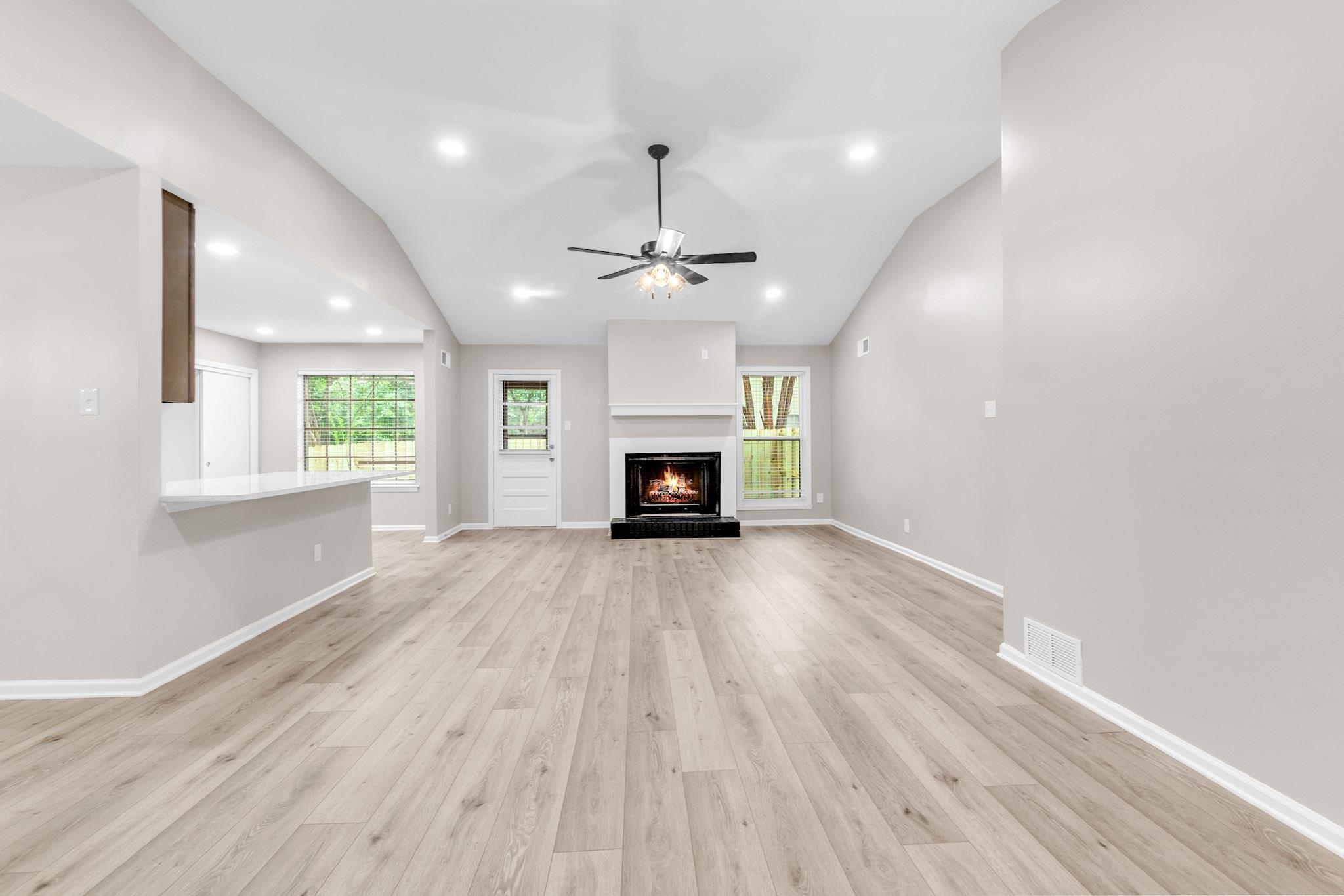 2556 Lynnfield Road Memphis, TN 38119 - Photo 15 of 24 Unfurnished living room with a lit fireplace, vaulted ceiling, ceiling fan, light wood-style floors, and recessed lighting