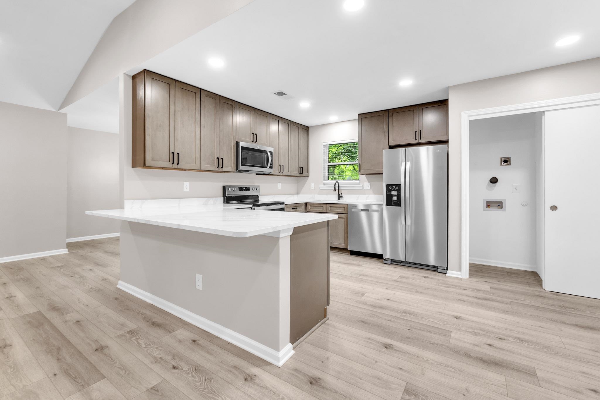 2556 Lynnfield Road Memphis, TN 38119 - Photo 21 of 24 Kitchen featuring stainless steel appliances, a peninsula, light stone countertops, light wood-style floors, and recessed lighting