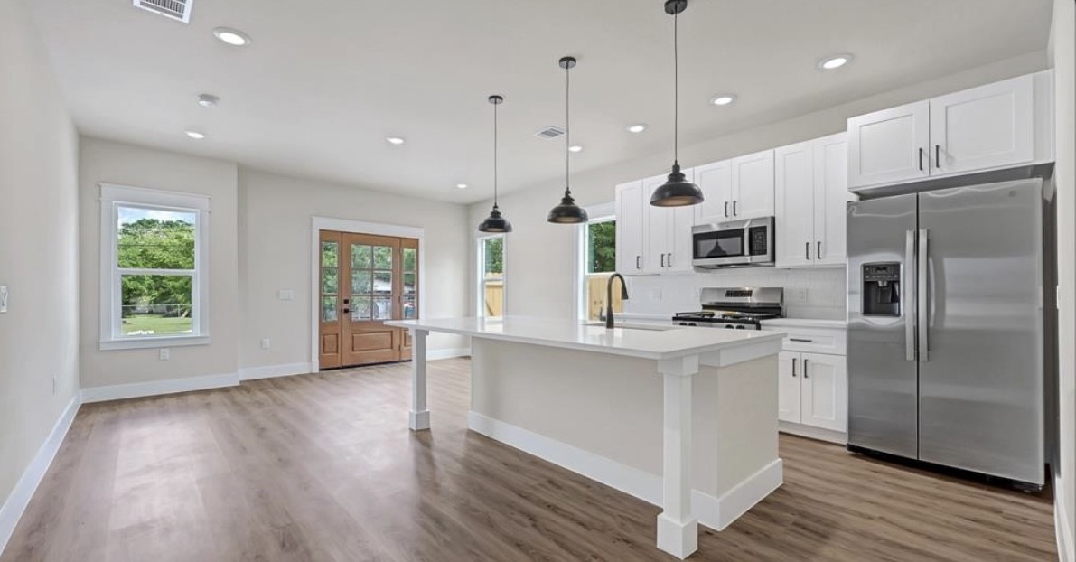 204 Booker T Washington Street, Unit B Conroe, TX 77301 - Photo 2 of 13 a kitchen with stainless steel appliances granite countertop a refrigerator a sink dishwasher a stove and white countertops with wooden floor