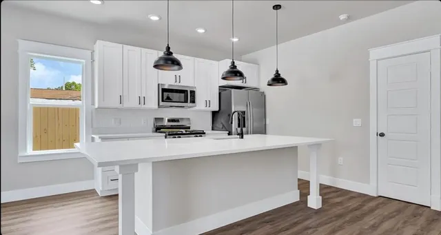 a kitchen with kitchen island a sink stainless steel appliances and wooden floor