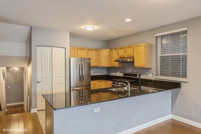 a kitchen with stainless steel appliances granite countertop a refrigerator a sink and a stove