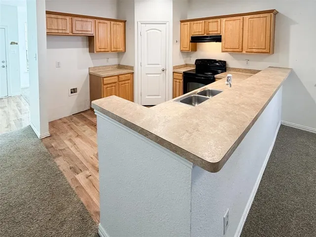 a kitchen with granite countertop a sink a stove and refrigerator