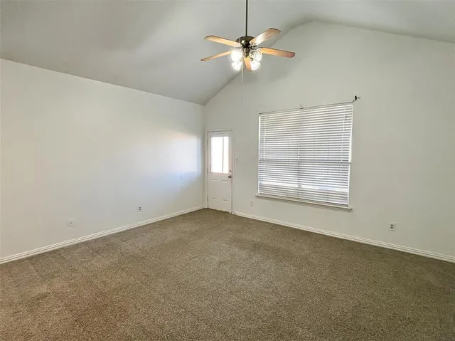 an empty room with a chandelier fan and windows