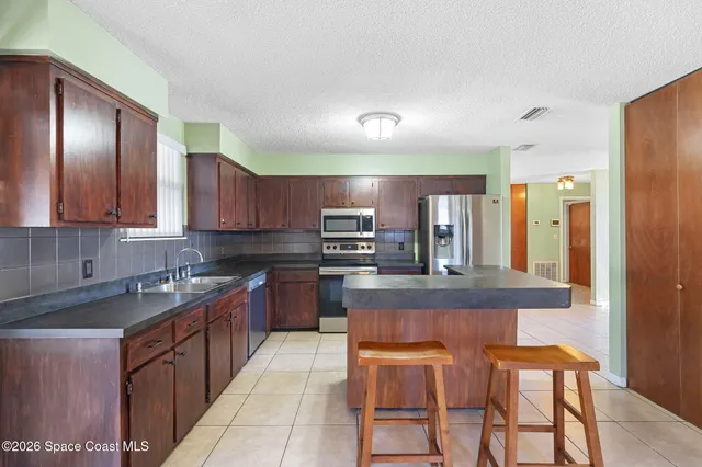 a kitchen with stainless steel appliances granite countertop a sink a stove and refrigerator