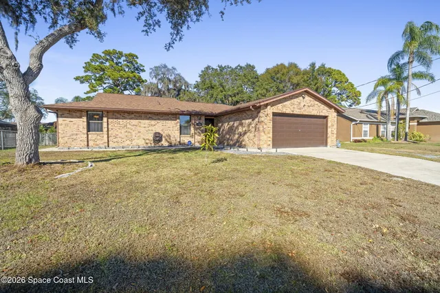 a view of house with backyard and trees in the background