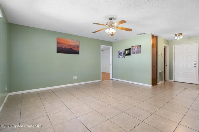 a view of an empty room with window and a kitchen