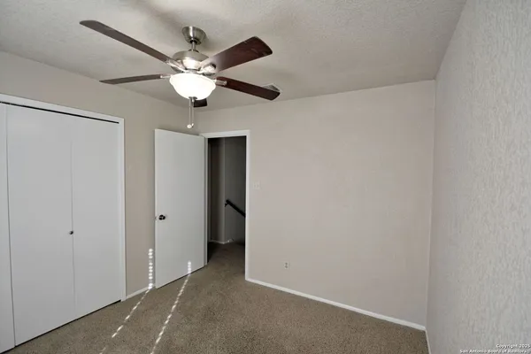 an empty room with a chandelier fan and windows
