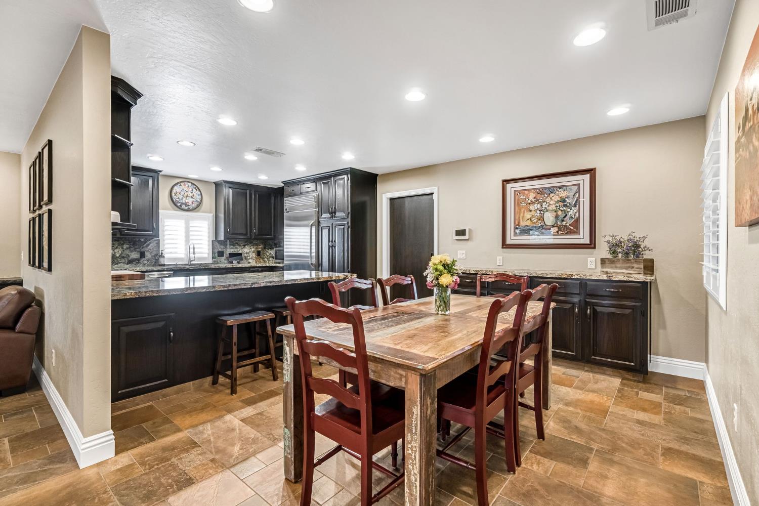 505 Ash Street Lemoore, CA 93245 - Photo 14 of 66 a kitchen with stainless steel appliances kitchen island granite countertop a dining table chairs and a refrigerator