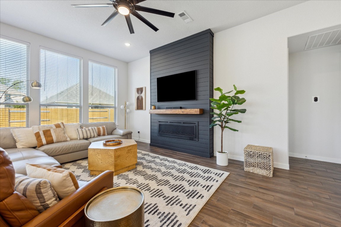 Welcome to this stunning property nestled in the prestigious Highlands at Mayfield Ranch community in Round Rock, Texas. The living room features an electric fireplace, modern grey shiplap accent wall, and mantle bringing out the relaxing atmosphere.