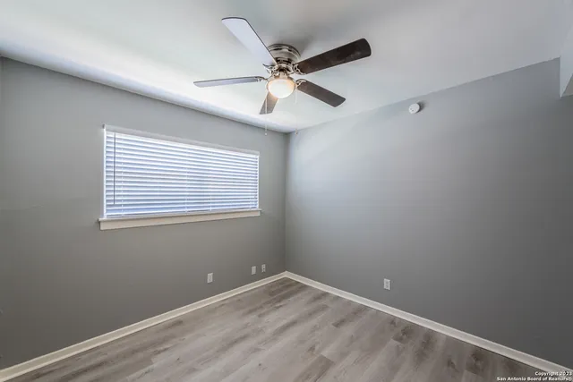 an empty room with a window and a fan