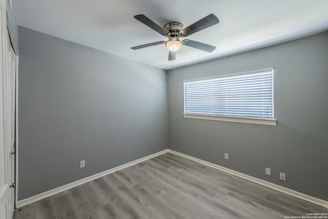 an empty room with a window and a fan