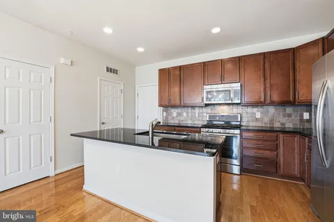 a kitchen with stainless steel appliances granite countertop a stove a sink and a white cabinets
