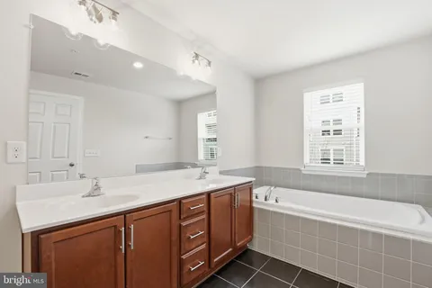 a spacious bathroom with a tub sink and mirror